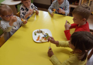 Dzieci nadziewają owoce na patyczki do szaszłyków.