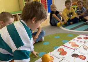 dziecko kładzie pomarańcze na obrazek z owocem