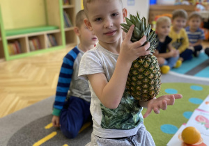 chłopiec pokazuje ananasa