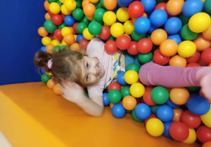 dziecko bawi się w kolorowych piłkach