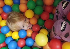 dziecko bawi się w kolorowych piłkach