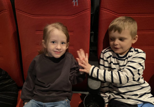 dzieci siedzą w fotelach i czekają na film