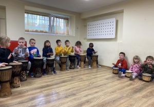 dzieci siedzą na ławce i grają na bębnach
