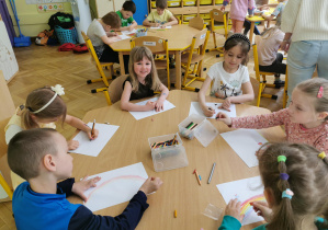 dzieci rysują obrazki siedząc przy stole, jubilatka uśmiecha się