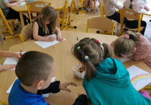 dzieci rysują obrazki siedząc przy stołach