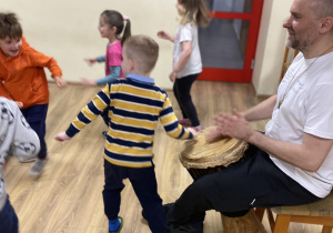 instruktor i chłopiec grają na bębnach a dzieci tańczą