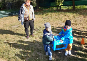 Dzieci biorą udział w zabawie ze skrzynkami.