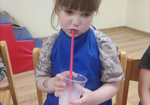 Dziewczynka pije sok z suchym lodem.