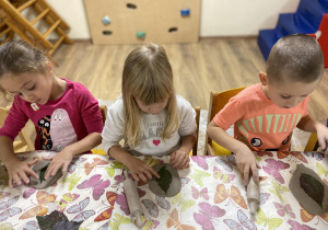 dzieci odciskają liście w glinie