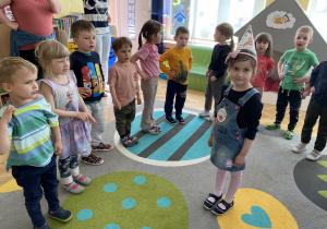 dzieci śpiewają sto lat a dziewczynka stoi na środku koła