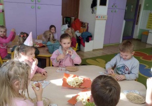 Dzieci jedzą urodzinowy poczęstunek