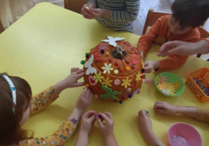 Dzieci dekorują dynię.