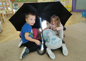 dzieci bawią się na dywanie z parasolkami