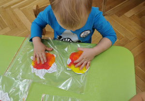dziecko maluje liście farbą przez folię