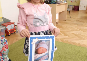 Dziewczynka prezentuje obrazek ilustrujący jedno z podstawowych praw dziecka.