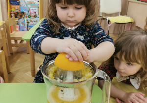 dziecko wyciska sok z pomarańczy