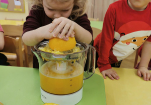 dziecko wyciska sok z pomarańczy