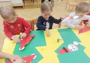 Dzieci robią Mikołaja z papieru.