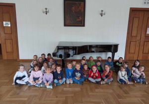 Zdjęcie grupowe "Misiów" i "Kotków" na tle fortepianu.