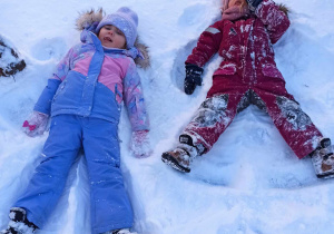 Dziewczynki robią "aniołki" na śniegu.
