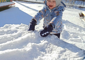 Chłopiec bawi się śniegiem.