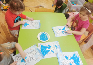 Dziecko maluje palcem zanurzonym w farbie sylwetkę "Pani Zimy".