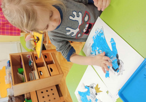 Dziecko maluje palcem zanurzonym w farbie sylwetkę "Pani Zimy".