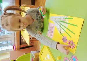 Dziecko robi kwiaty z papieru.
