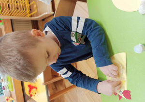 Dziecko wykonuje kurkę z papieru.