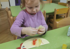Dziecko wykonuje kurkę z papieru.