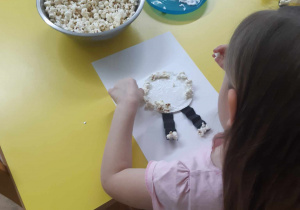 Dziecko wykonuje owieczkę z popcornu.