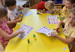 dzieci siedzą przy stole i wycinają